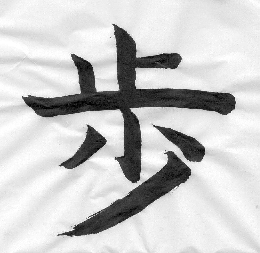 Calligraphie du kanji 歩 (marcher), illustrant l'écriture des caractères chinois.