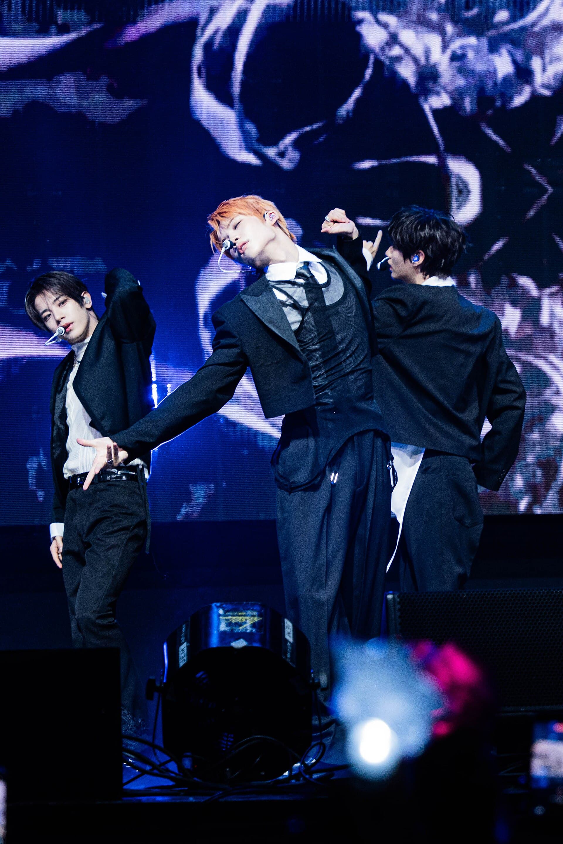 Groupe de K-pop en concert, chorégraphie dynamique sur scène.