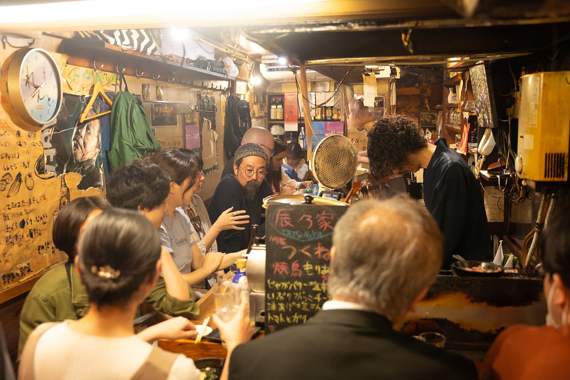 Comptoir bonde d'un izakaya de la ruelle Omoide Yokocho a Shinjuku, avec ardoise manuscrite des plats et clients serres autour du grill