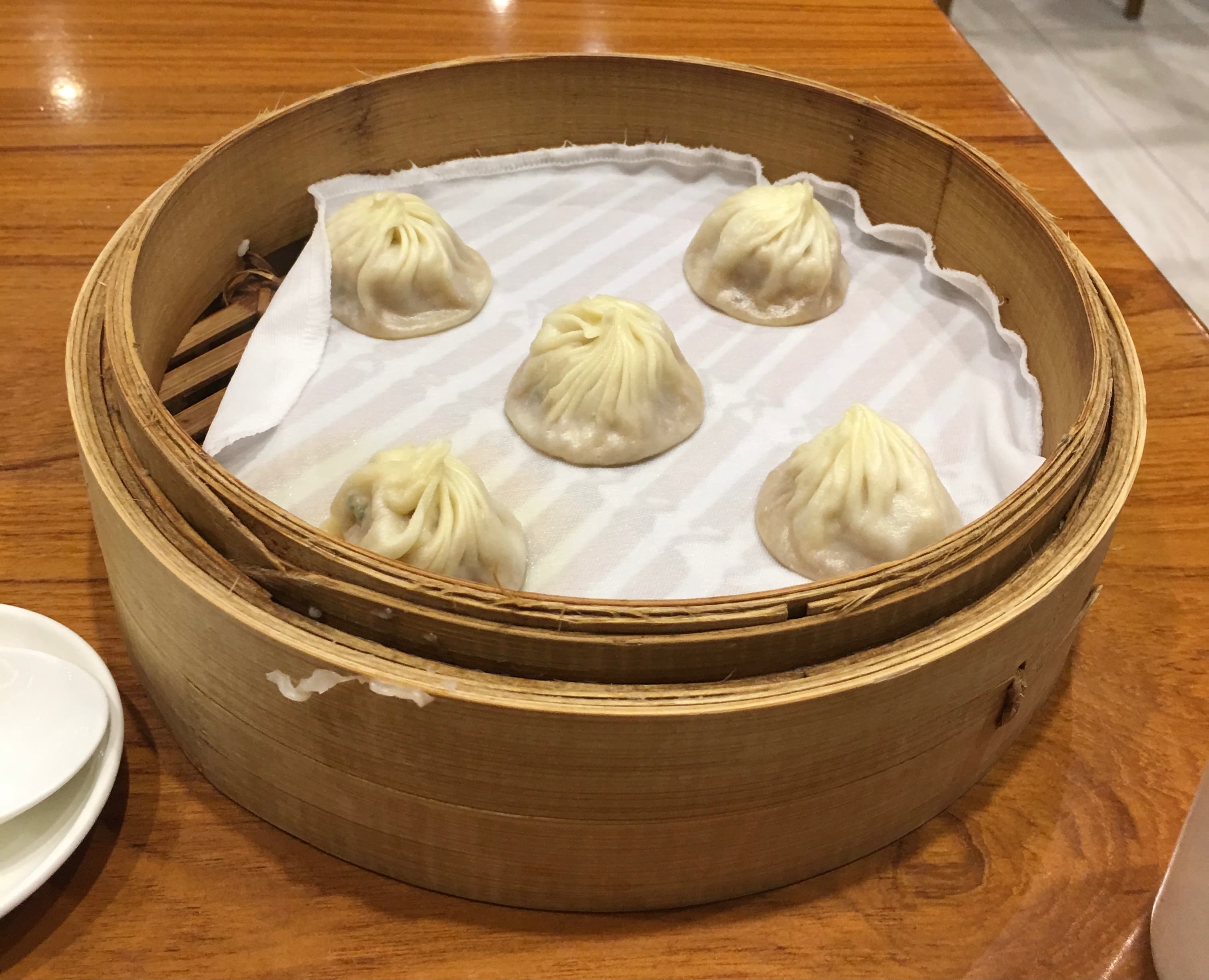 Xiaolongbao (raviolis à la soupe) servis dans un panier vapeur en bambou chez Din Tai Fung.