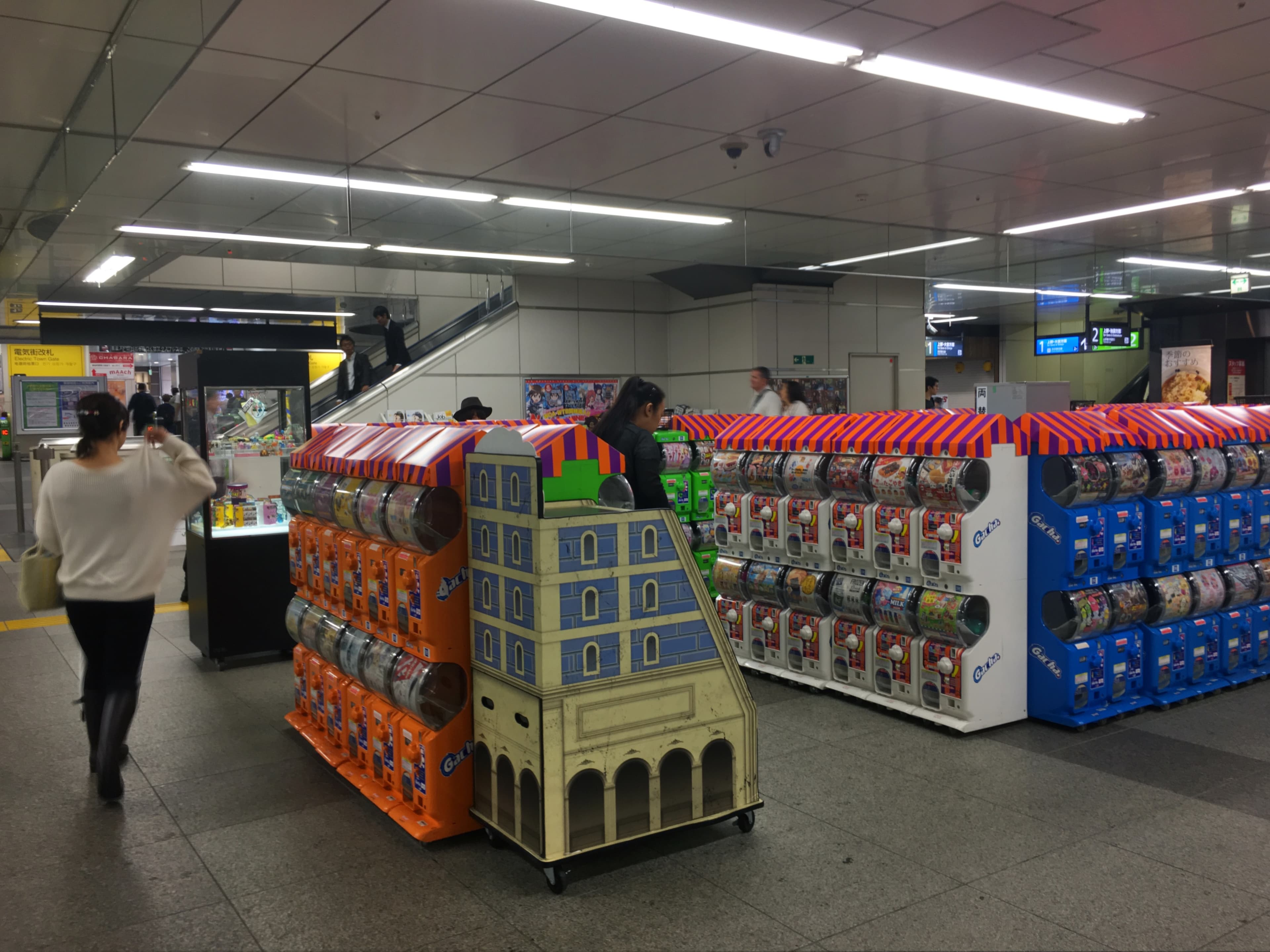 Mur de distributeurs de gachapon colorés alignés dans une gare d’Akihabara à Tōkyō.
