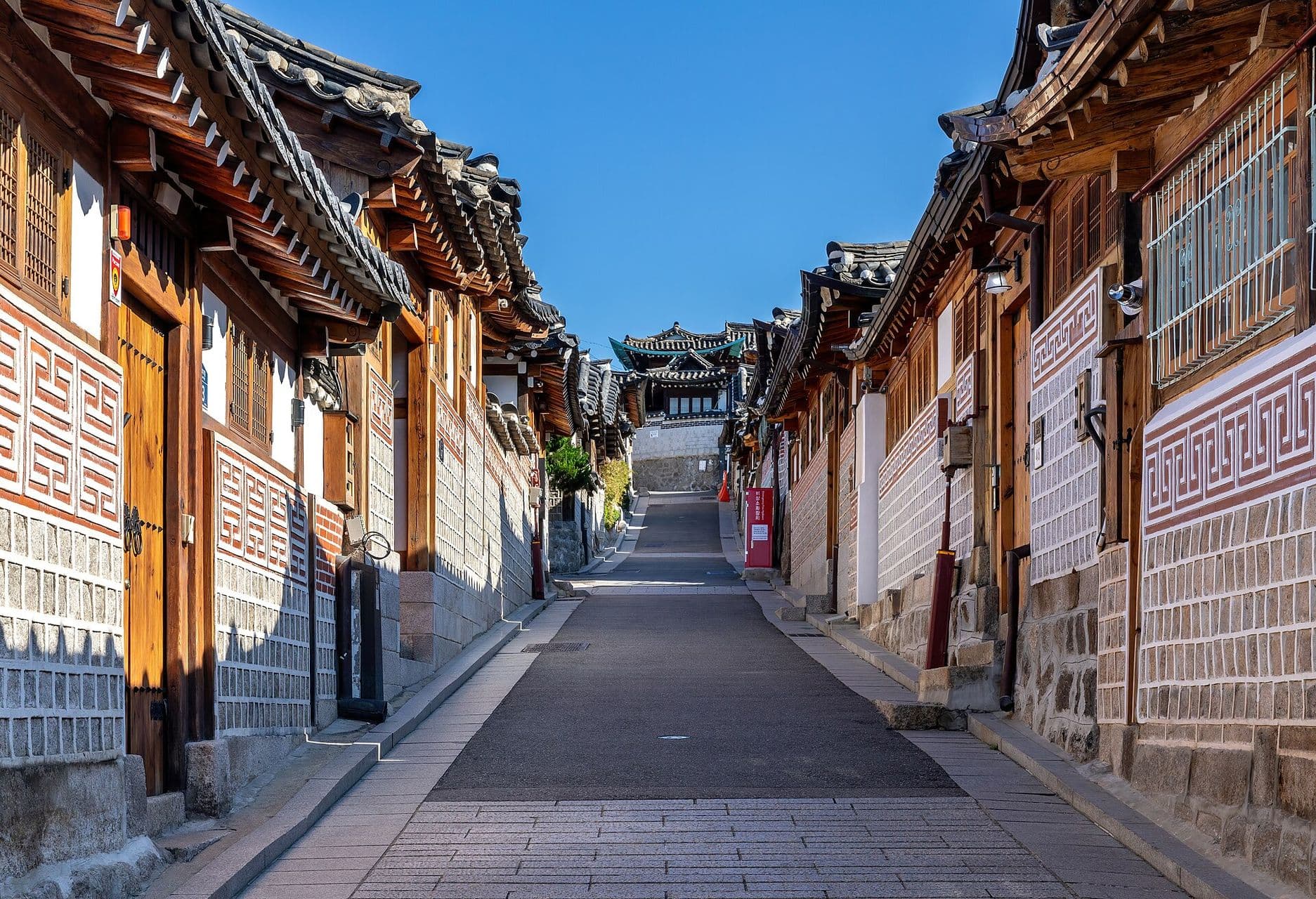 Rue de maisons hanok du quartier de Bukchon, à Séoul, sous un ciel bleu.