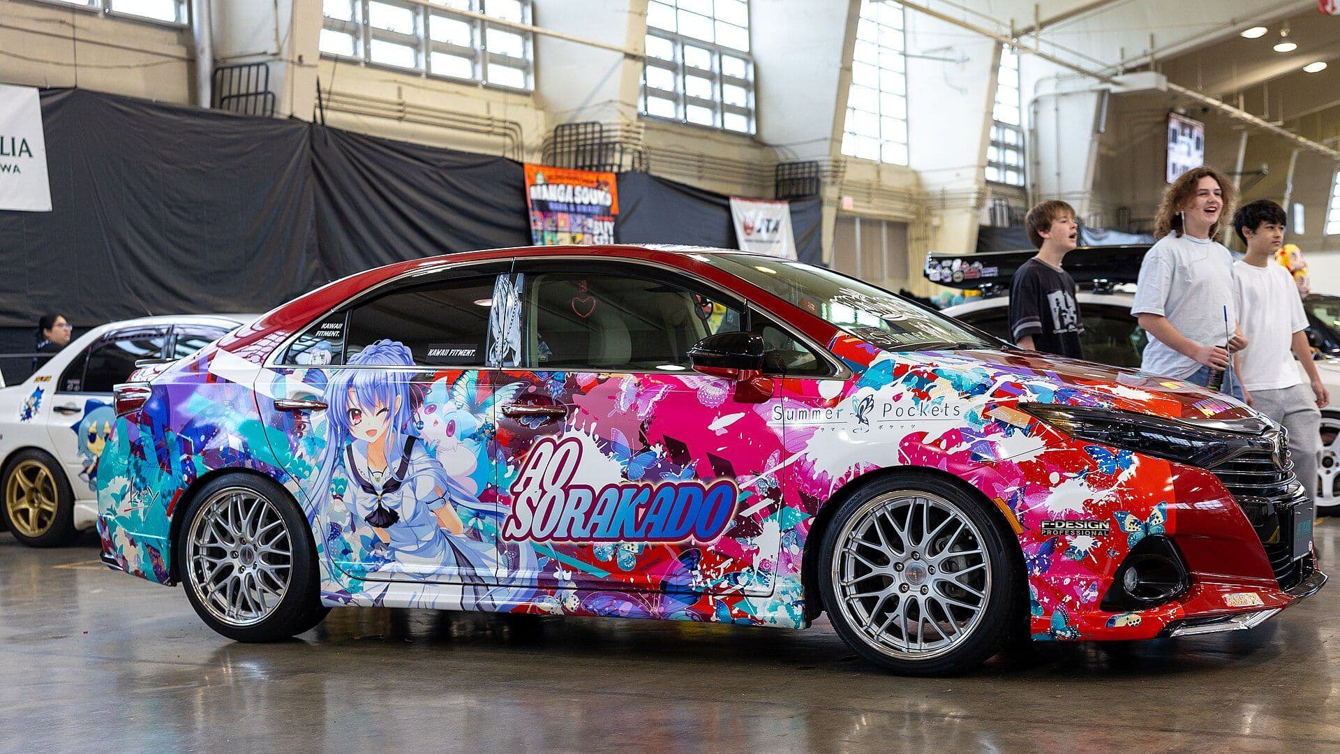 Voiture itasha couverte d'illustrations de personnages, exposée lors d'un salon au Japon.