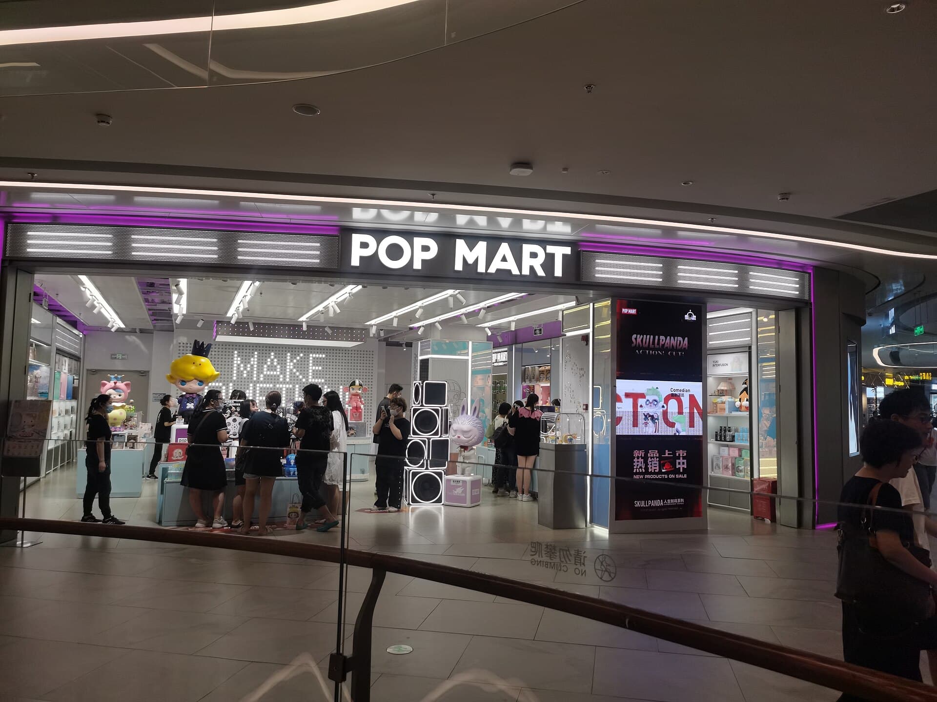Devanture d'une boutique Pop Mart dans un centre commercial chinois, avec ecran promotionnel de la serie Skullpanda et statues de personnages a l'entree