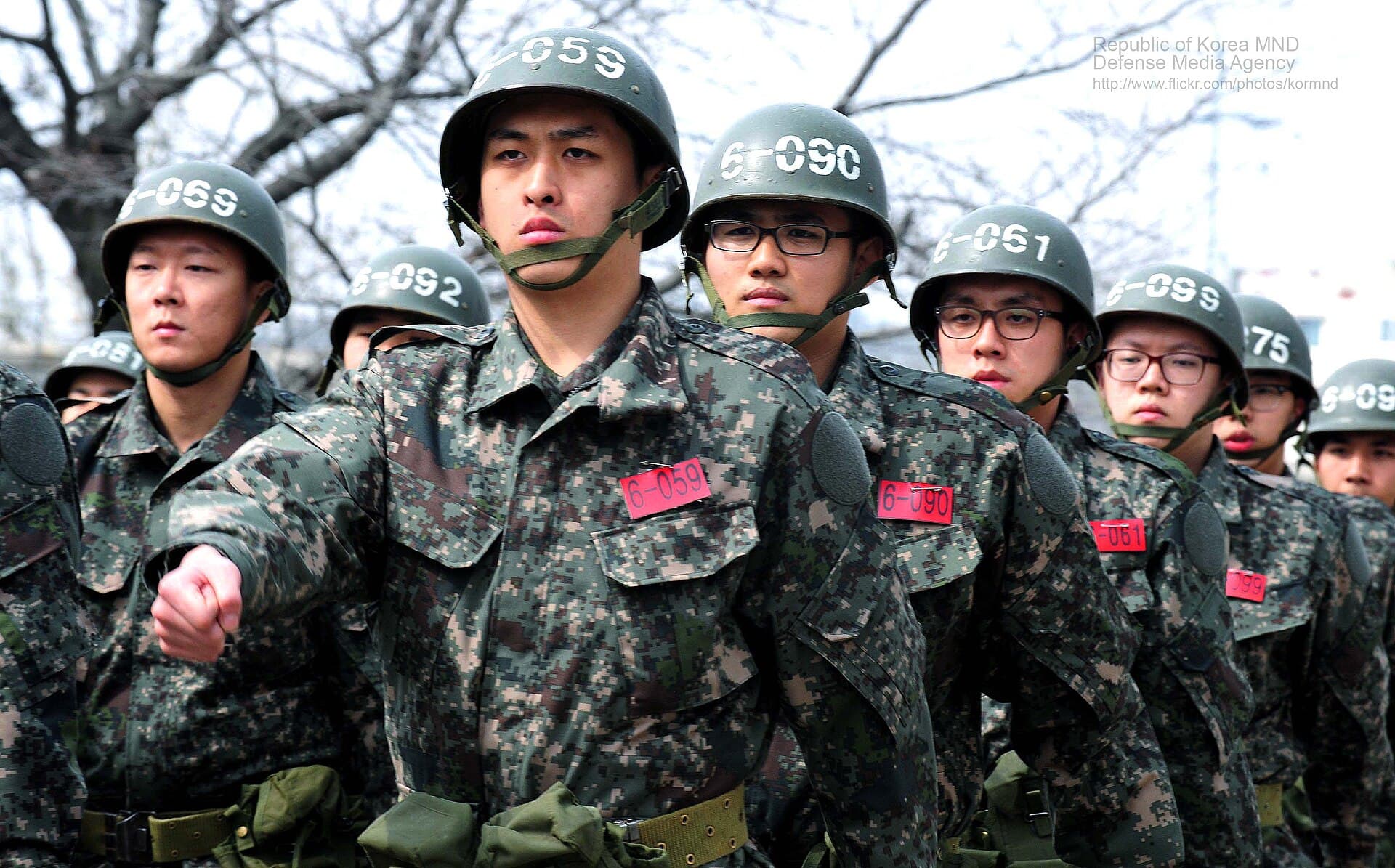Recrues du centre d'instruction de l'armee de terre sud-coreenne a Nonsan en rang serre pendant un exercice d'ordre serre, casques numerotes et badges rouges d'identification sur la vareuse de treillis