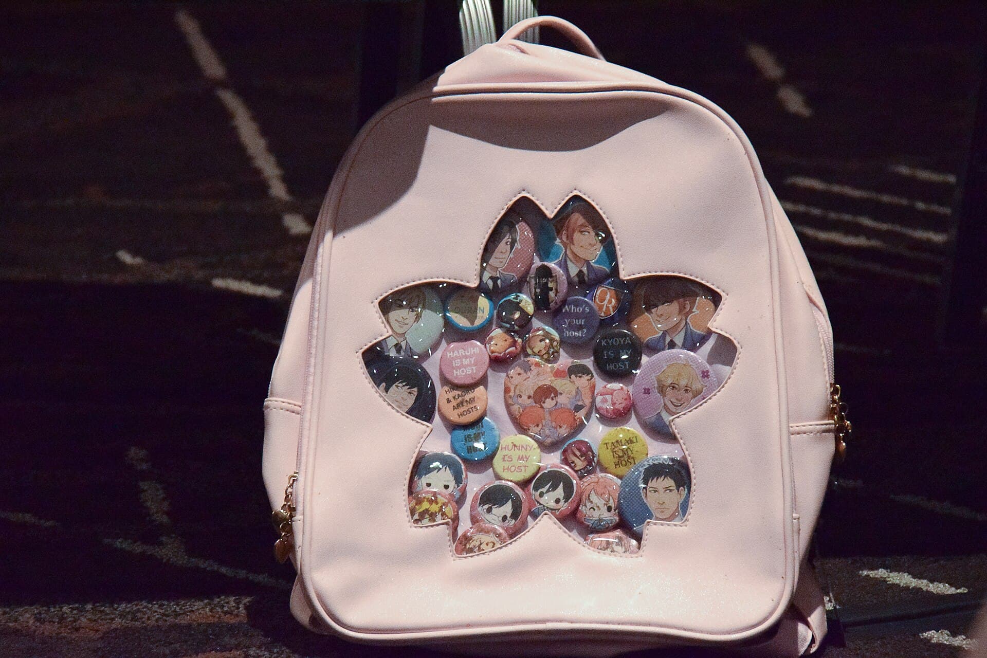 Sac itabag rose couvert de badges a l'effigie des personnages preferes d'une serie animee, dont plusieurs proclament le nom du favori