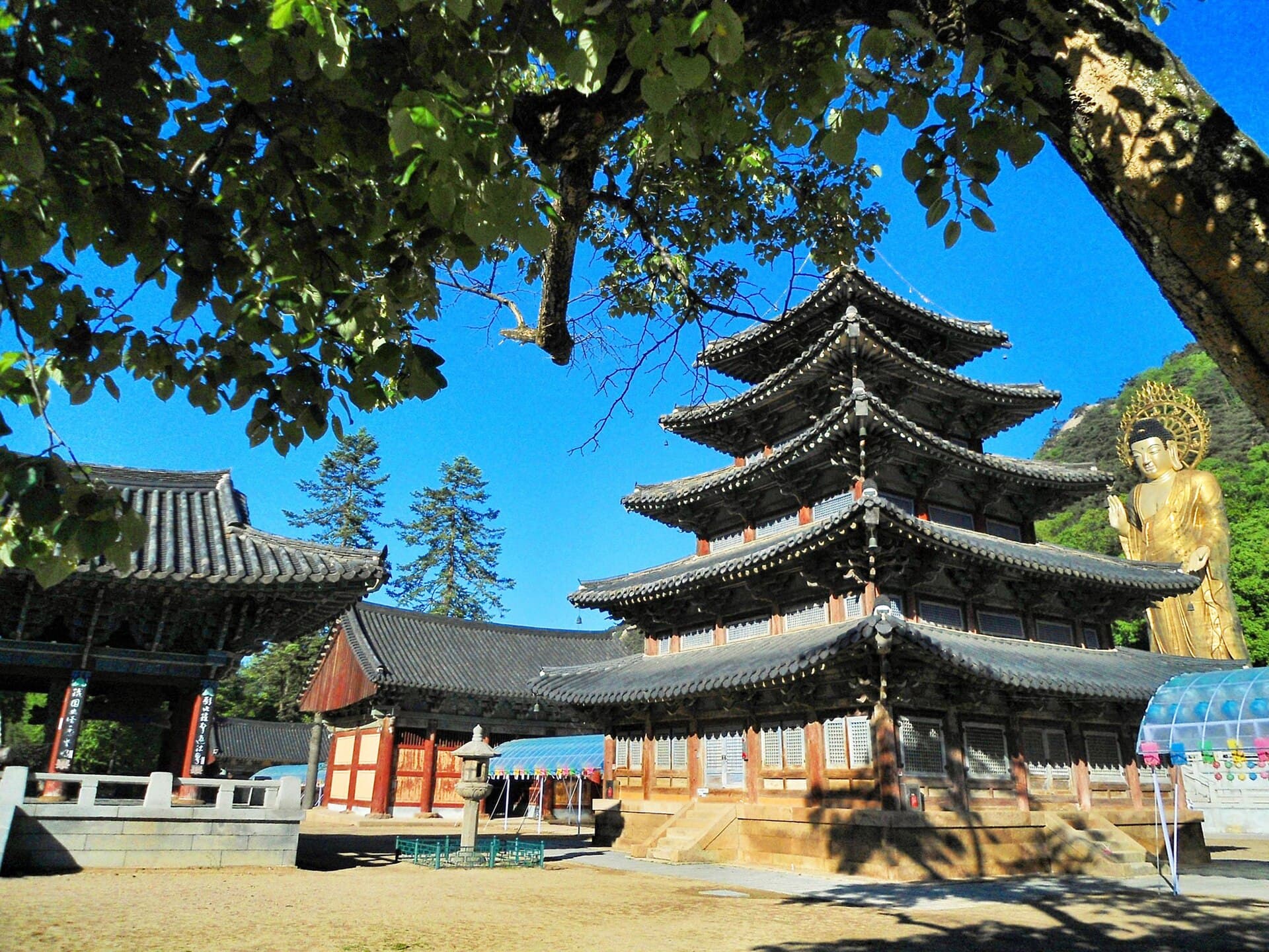 Cour du temple bouddhiste de Beopjusa, avec le pavillon de bois a cinq etages Palsangjeon et le grand Bouddha dore en arriere-plan