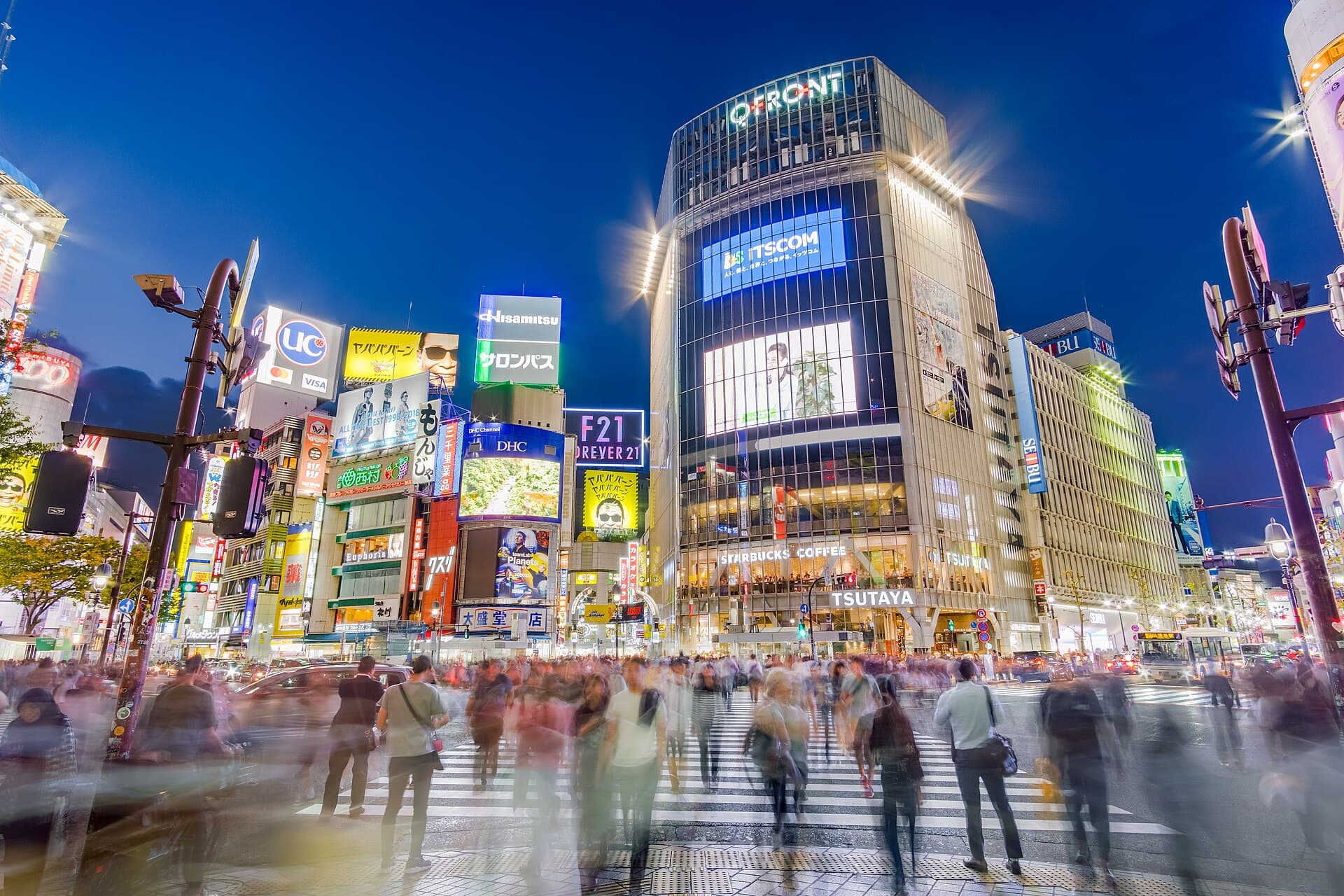 Le carrefour en diagonale de Shibuya a Tokyo vu depuis la place Hachiko, traverse par une foule dense sous les ecrans publicitaires des immeubles