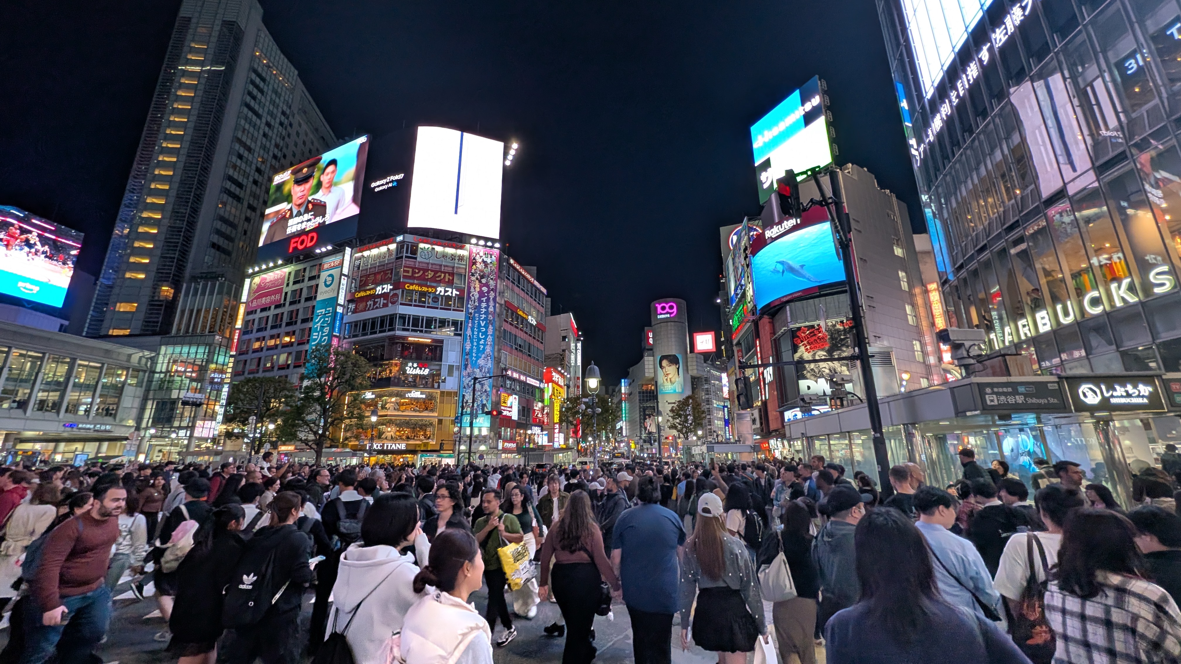 Shibuya crossing lit up at night, the screens and neon of Tōkyō, a visual backdrop associated with the city pop revival