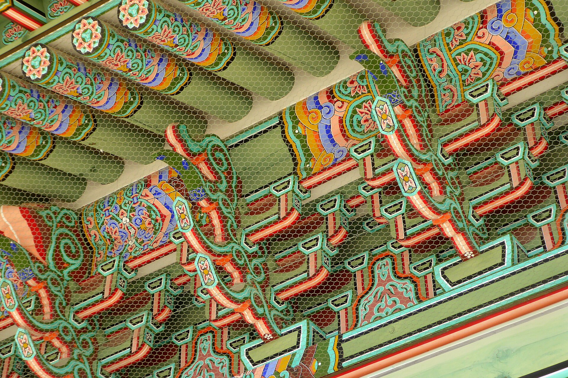 Detalle de alero pintado de un templo coreano: motivos florales meoricho en los extremos de los cabrios, degradados azules y rojos perfilados de negro