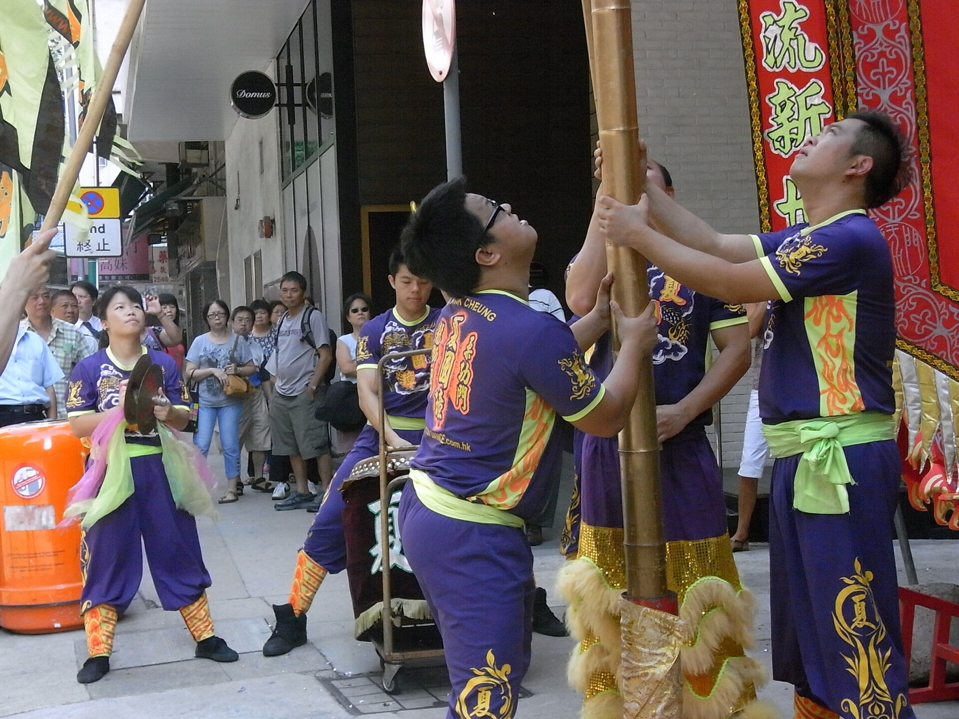 Inauguración de un negocio chino en un día fasto, con danza del león y guirnaldas rojas ante el escaparate