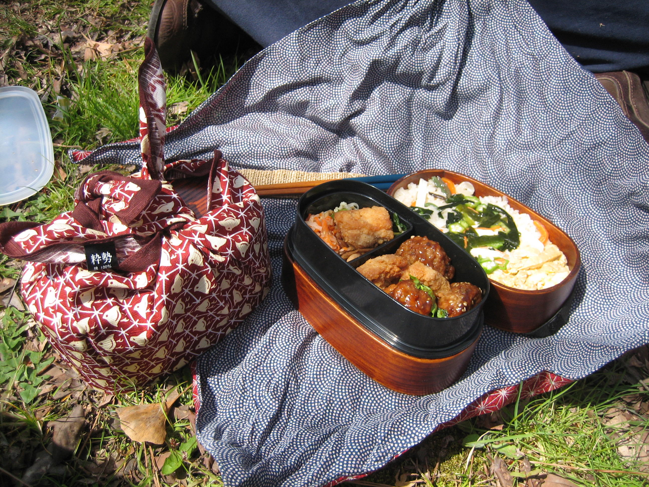 Japanese bentō lunch box wrapped and knotted in a patterned furoshiki cloth, ready to be carried