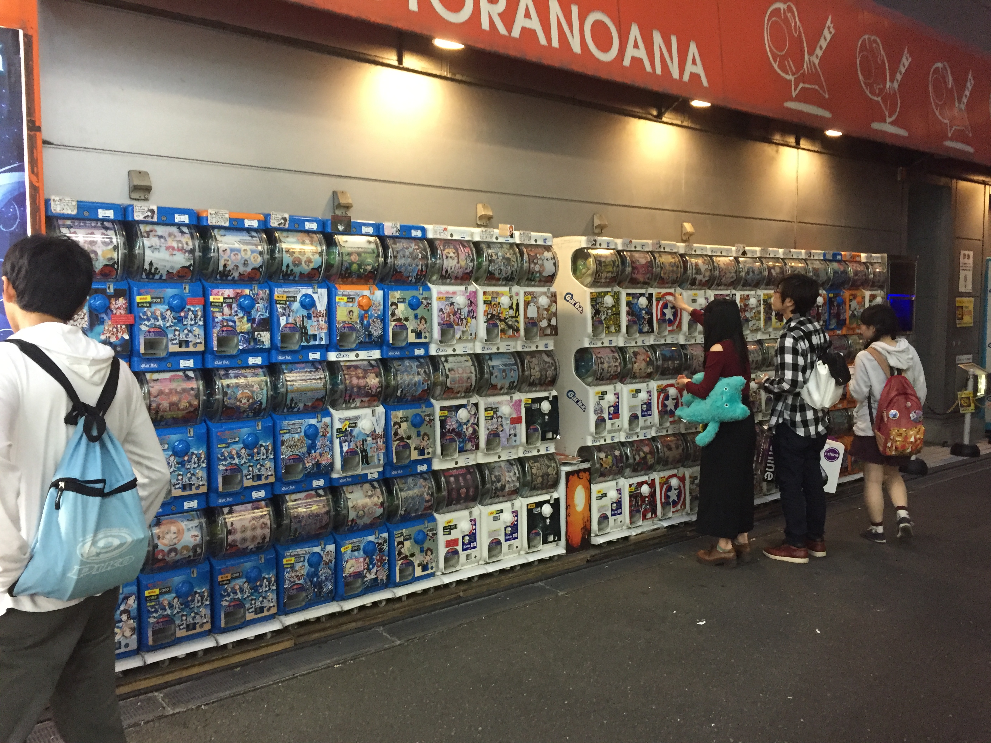 A wall of colorful gachapon machines lined up in a Tōkyō shop