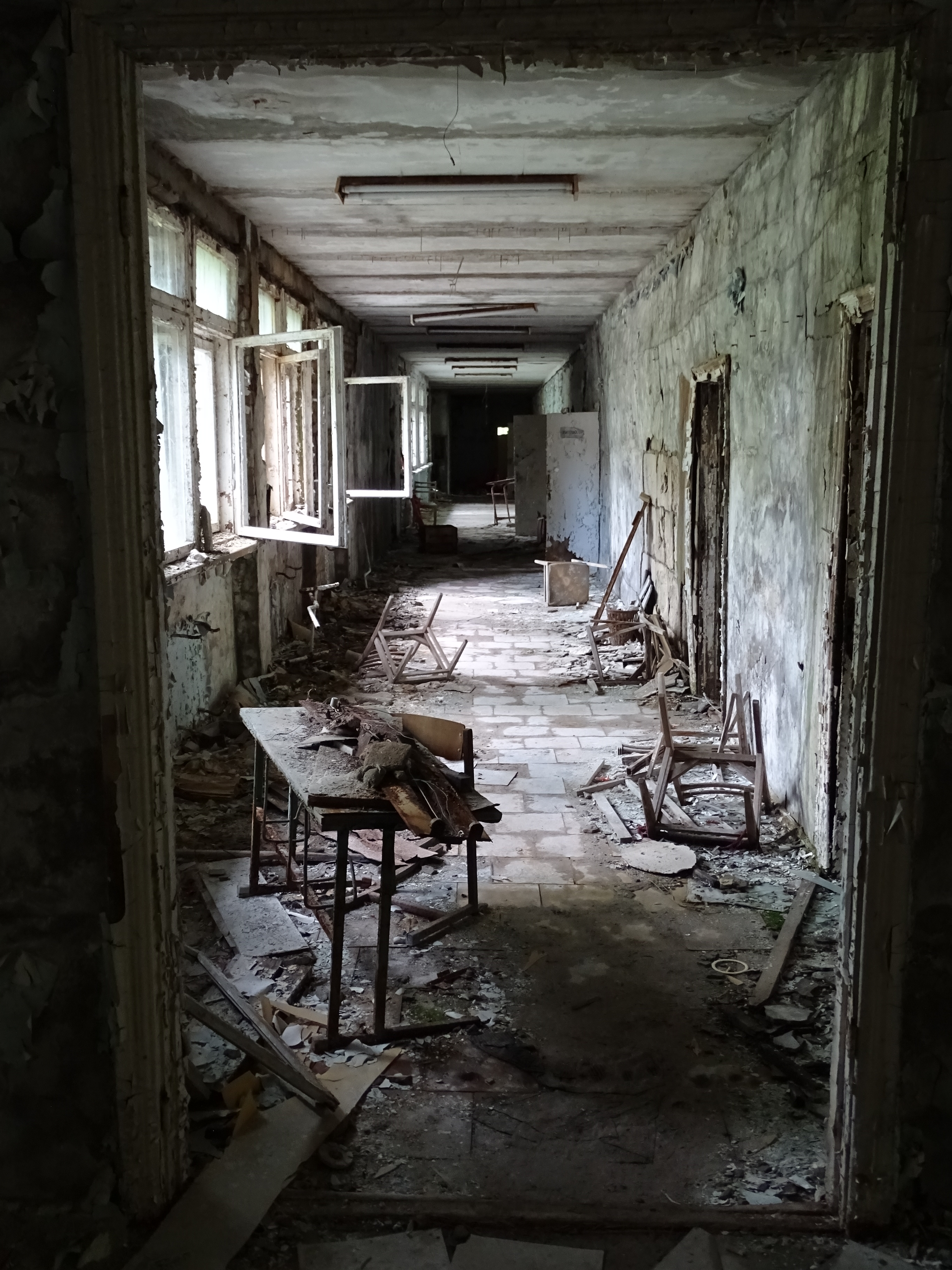 Corridor of an abandoned school, empty classrooms and pale light evoking the oppressive atmosphere of the haunted high schools of indie horror