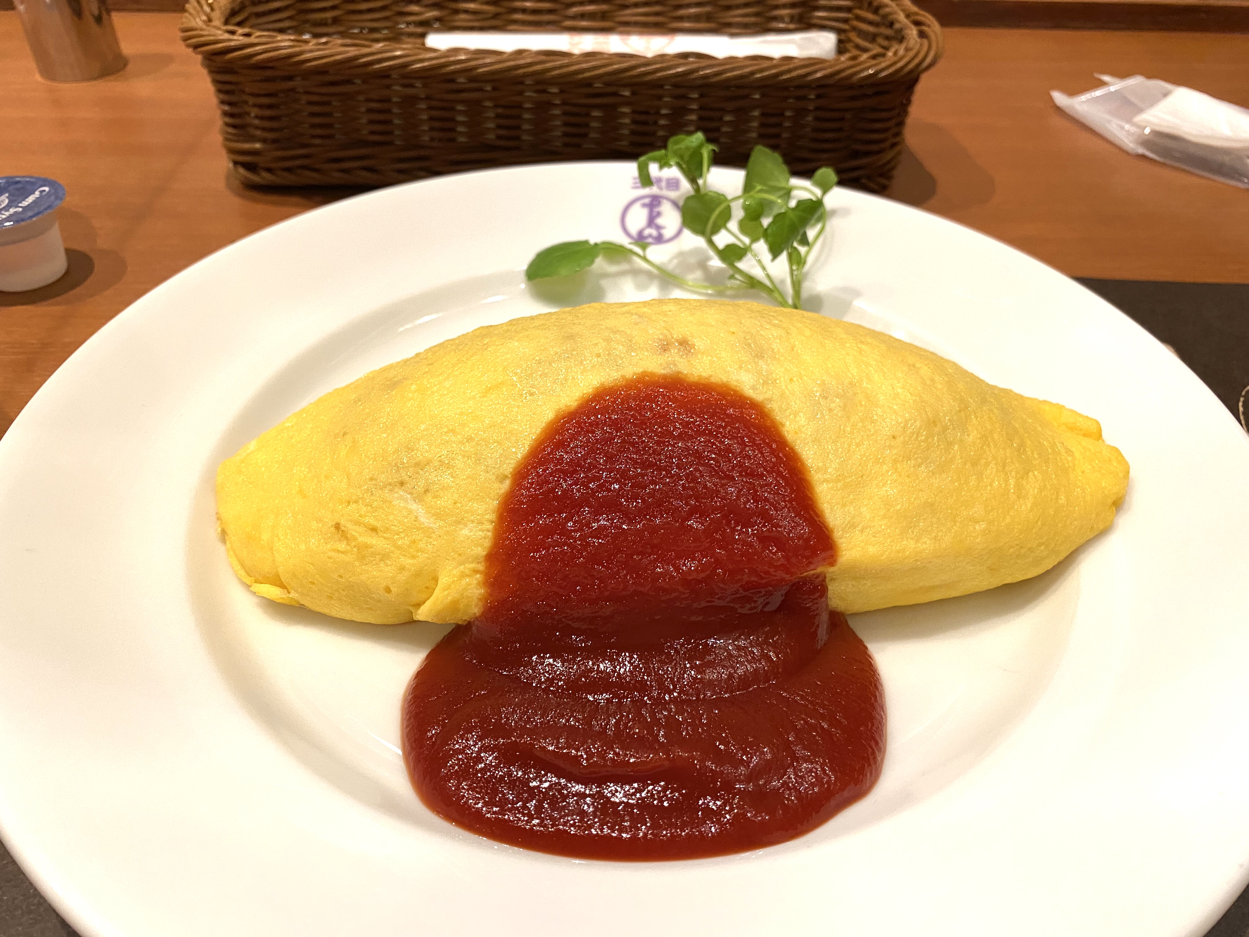 Omurice topped with ketchup, an omelette wrapped around rice, the signature dish of maid cafés