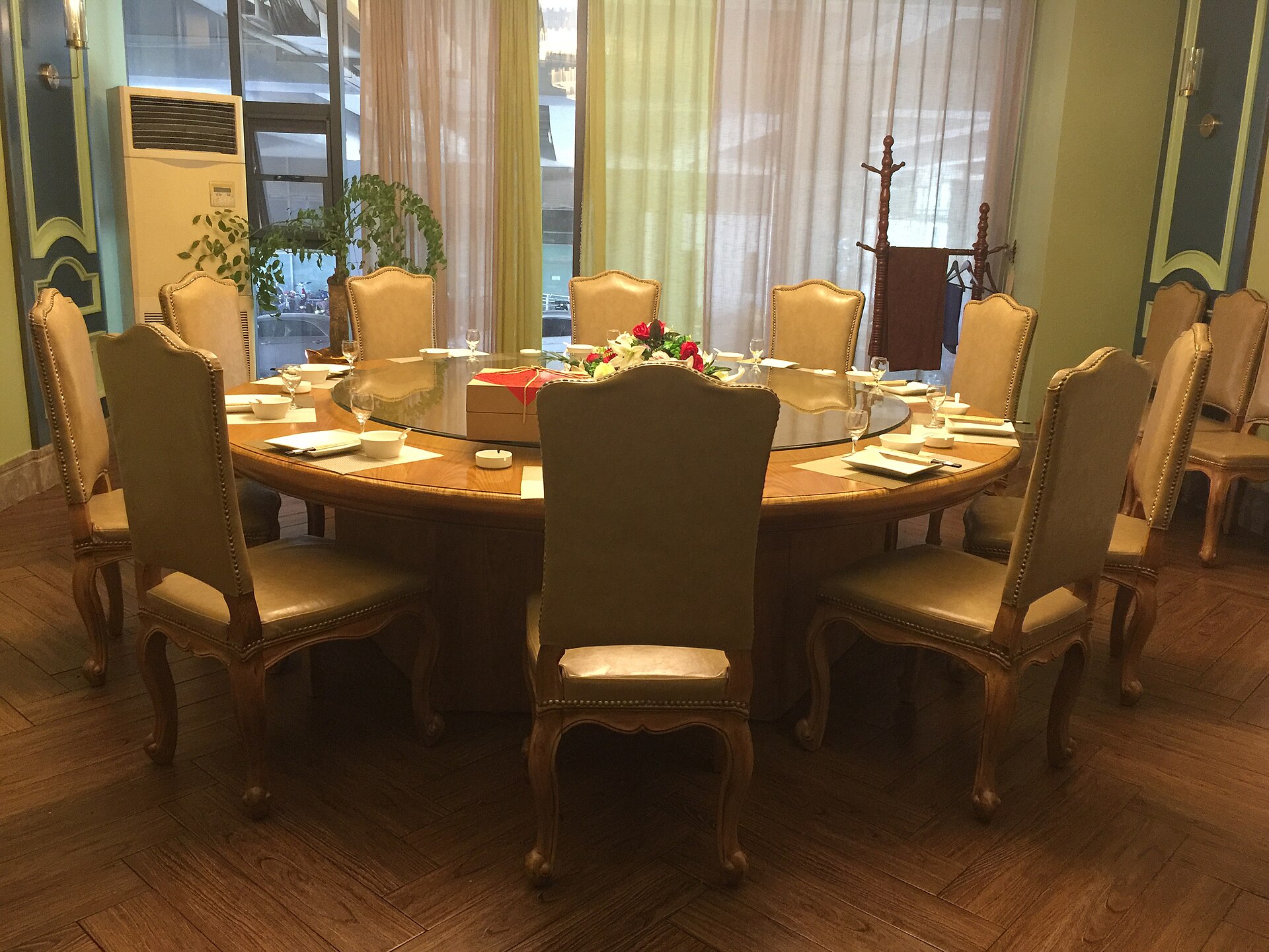 Gran mesa redonda de un banquete chino en un hotel de Hong Kong, platos compartidos en el centro sobre una bandeja giratoria, cubiertos y copas dispuestos para los comensales