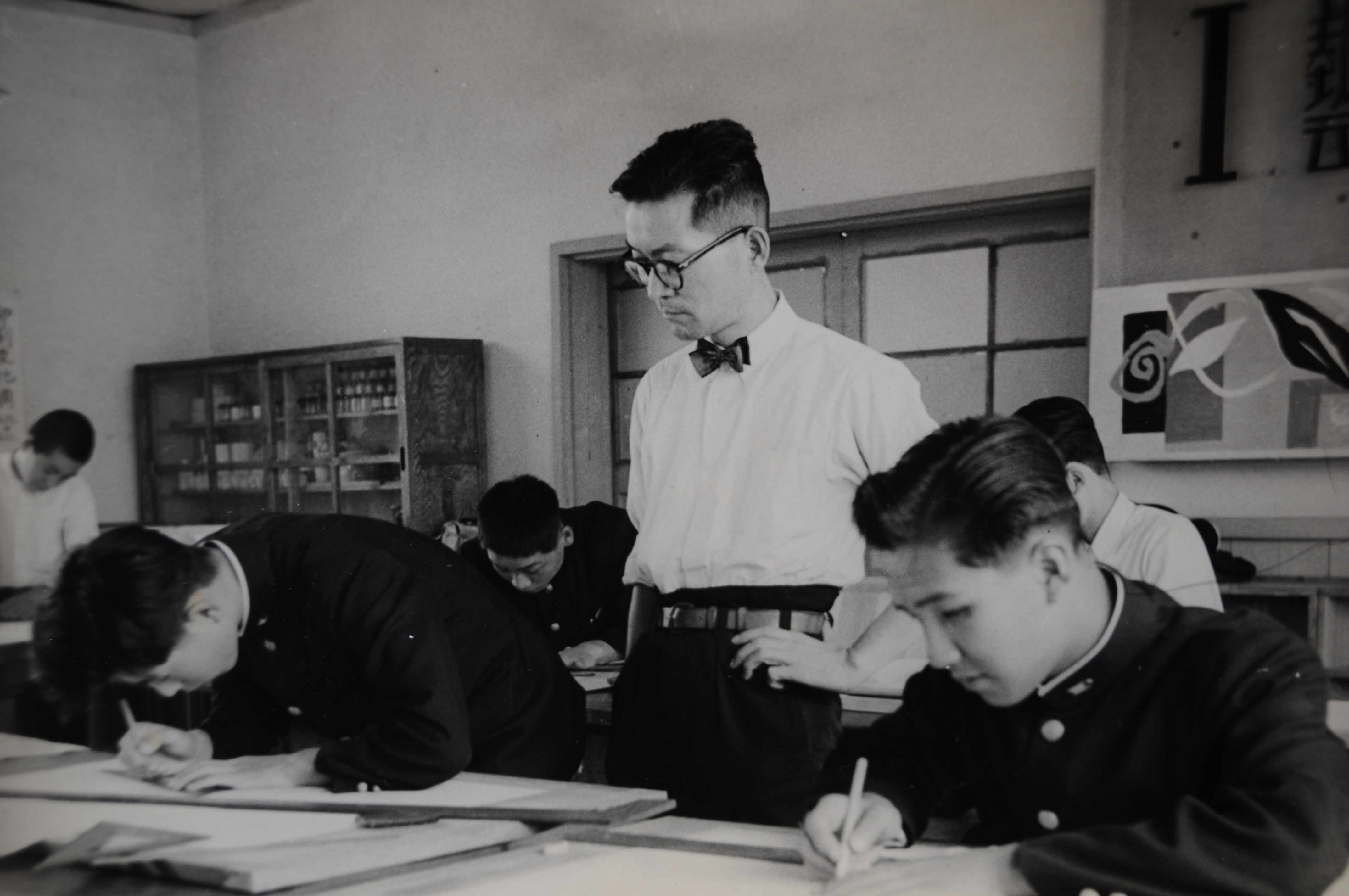 Japanese high schoolers in uniform working at their desks with textbooks open in a classroom