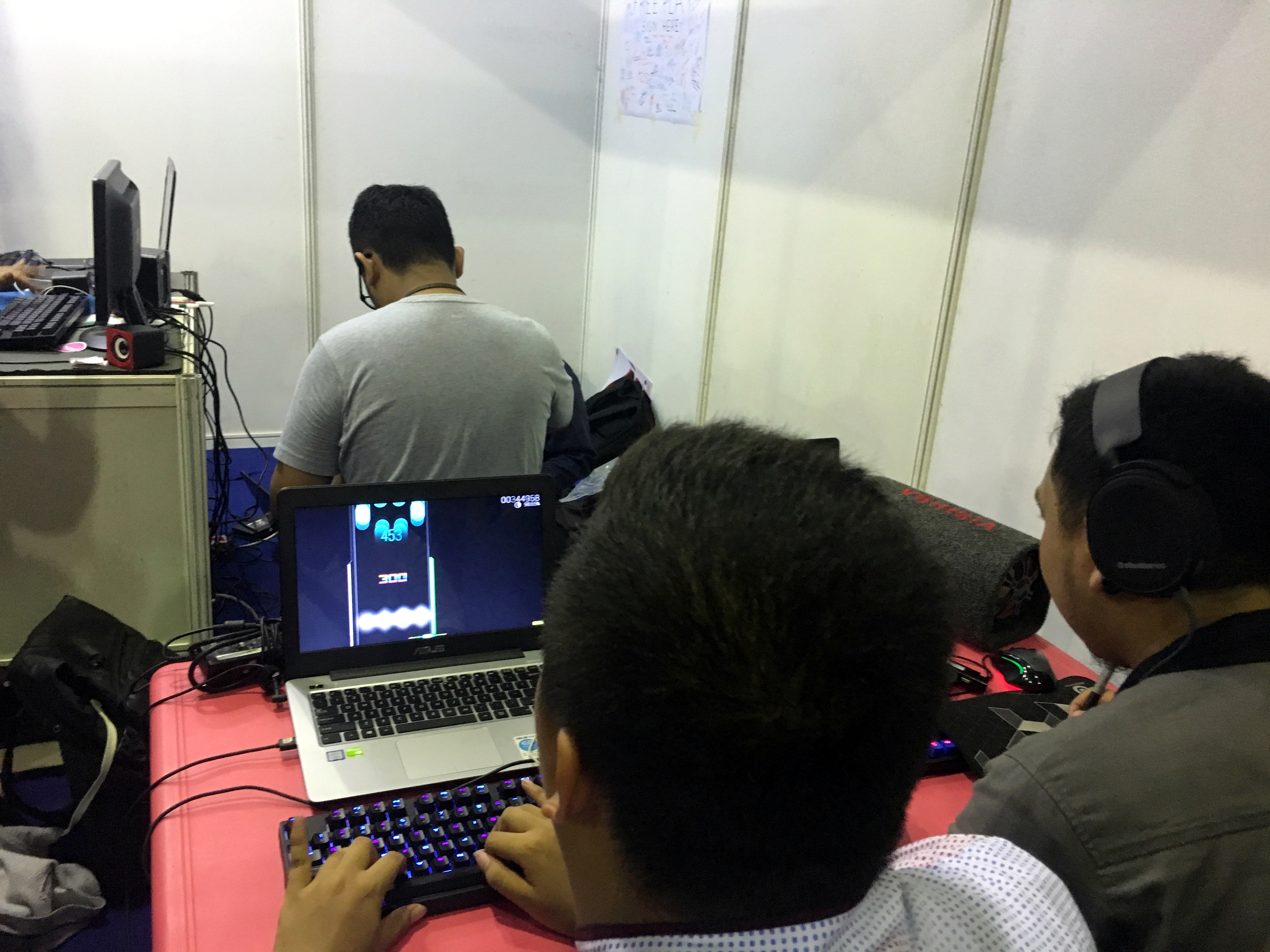 A player focused on the rhythm game osu! at a convention